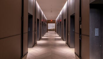 Modern corridor lined with energy-efficient elevators using destination dispatch for improved energy savings.