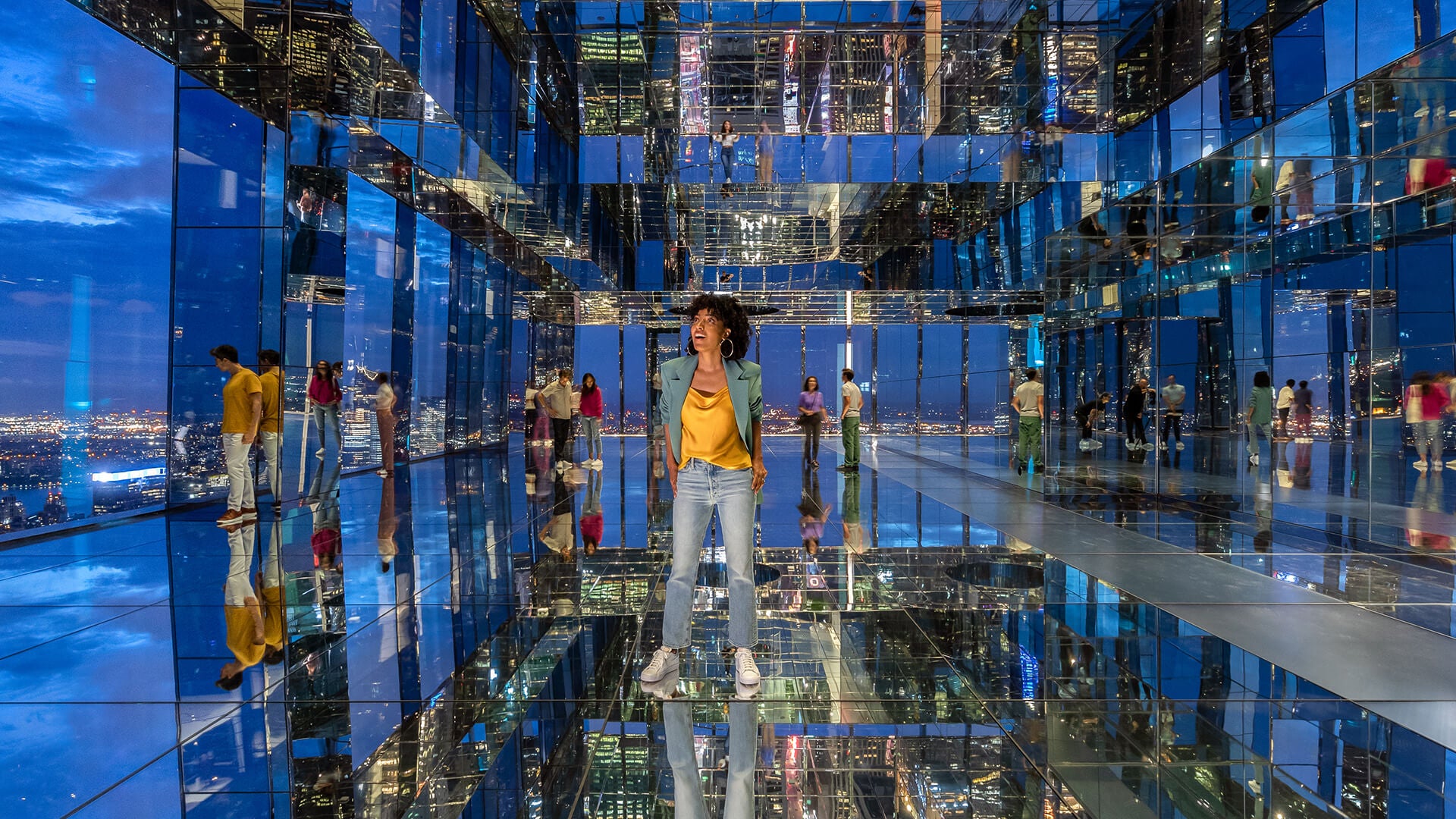 A woman marvels at the New York nightscape in a room of mirrors, where the city's lights multiply infinitely.