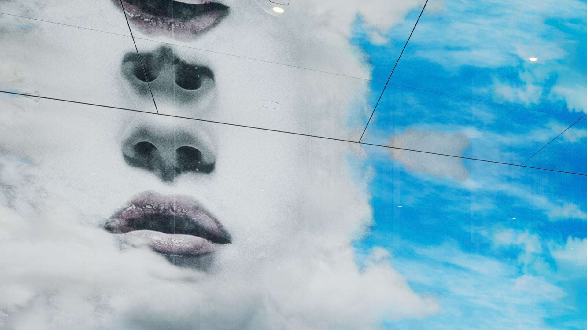 A striking digital art facade merges a woman's features with clouds, blending her face seamlessly with the sky.