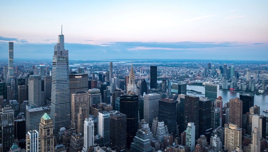 Aerial view of the New York City skyline at sunset, showcasing iconic skyscrapers and the river.